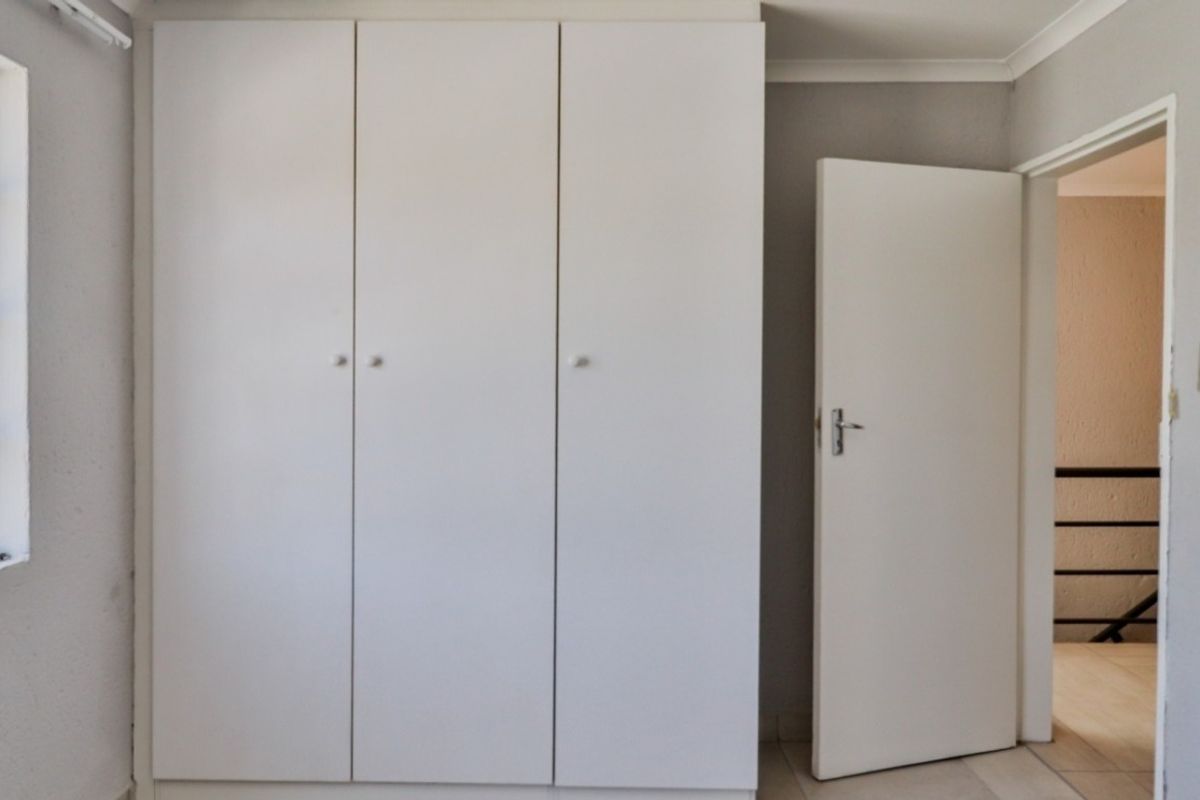 A clean, empty bedroom featuring a white built-in wardrobe and neutral wall finishes, offering a blank canvas for personalization.