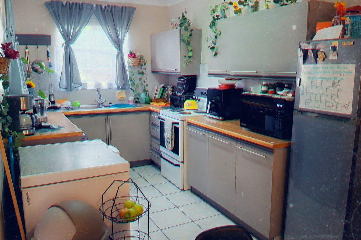 A functional kitchen featuring built-in cabinetry, laminate countertops, a stainless steel sink, and tiled flooring, providing a practical workspace for daily meal preparation.