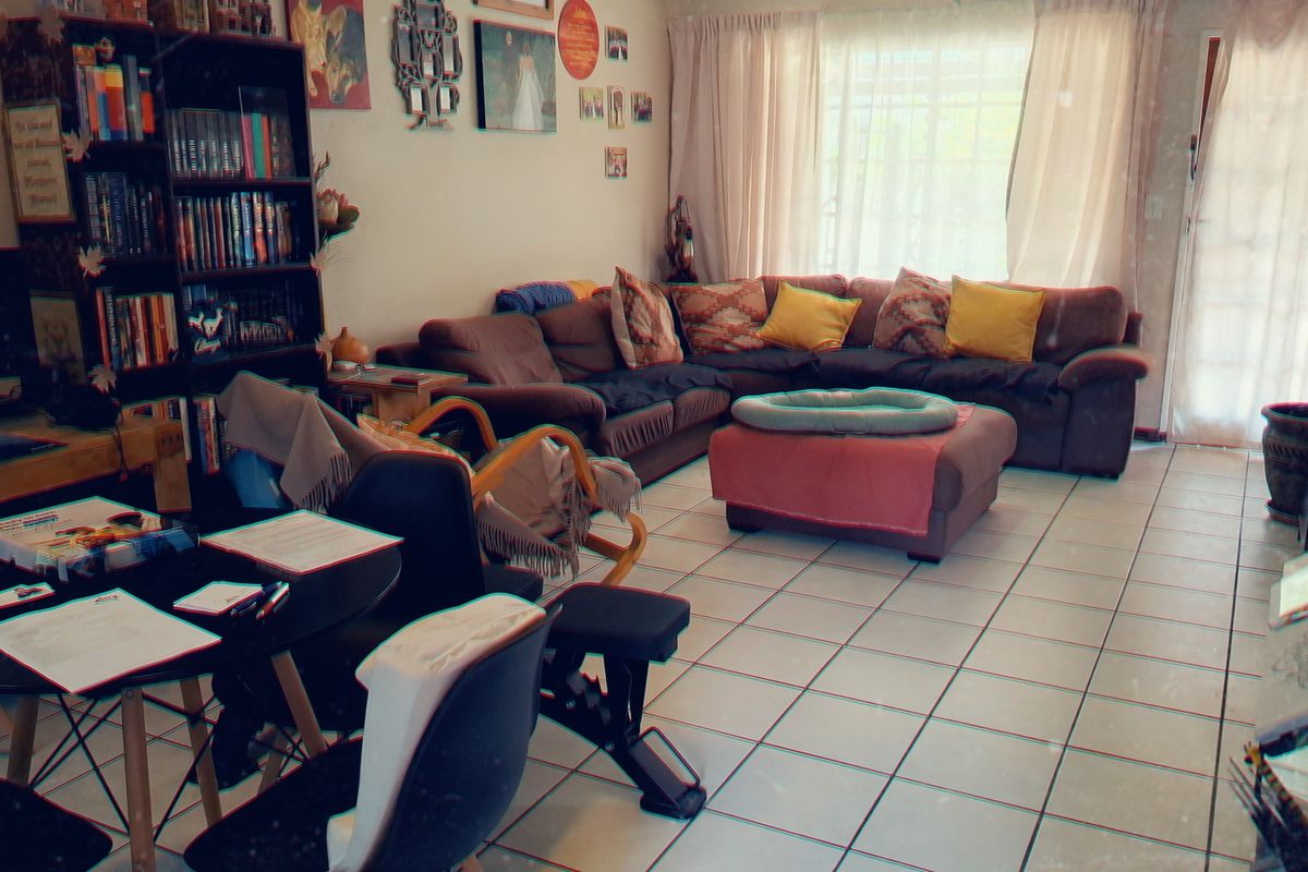 A spacious living room featuring tiled flooring and a sliding glass door providing natural light.