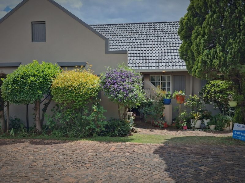 Front elevation of a small holding property featuring a gabled roofline, paved driveway, and established garden landscaping.