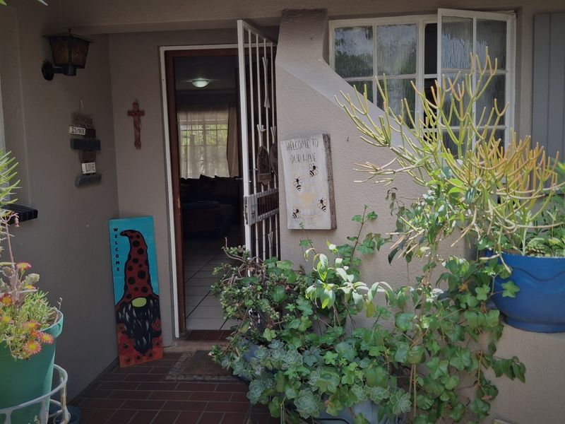 A welcoming entrance area featuring a security gate, tiled flooring, and exterior lighting, providing access to the main living space.