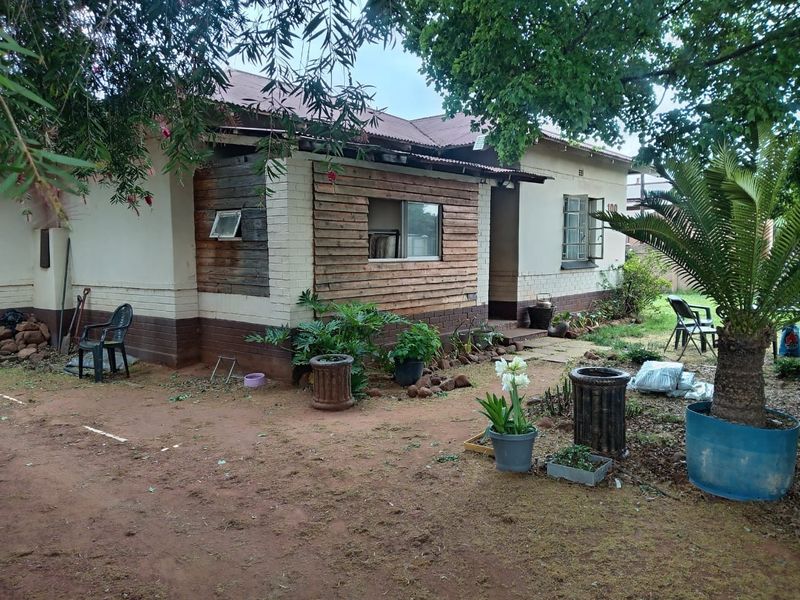 Rear view of a single-story house featuring a combination of brick and timber cladding with a corrugated metal roof.