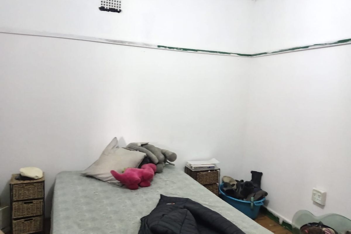 A bedroom featuring white walls with a picture rail and a high-level air vent, requiring cosmetic updates to improve the overall finish.
