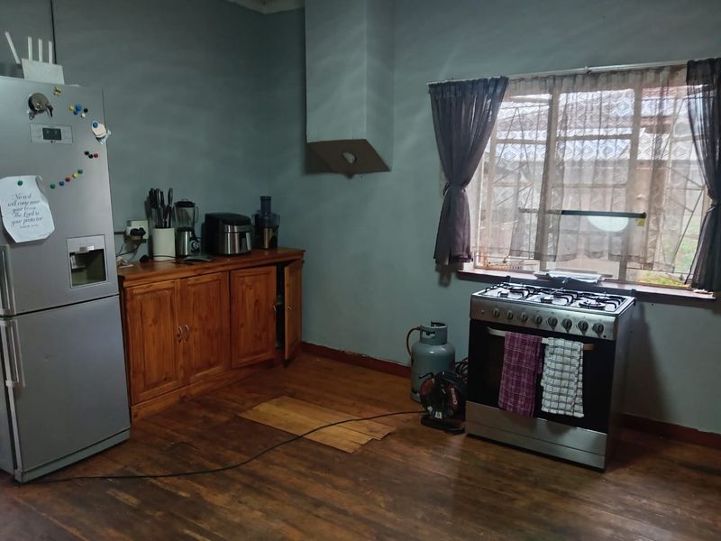 Kitchen area featuring wooden cabinetry, a gas stove, and a window with security bars. The space requires flooring repairs and cosmetic updates.
