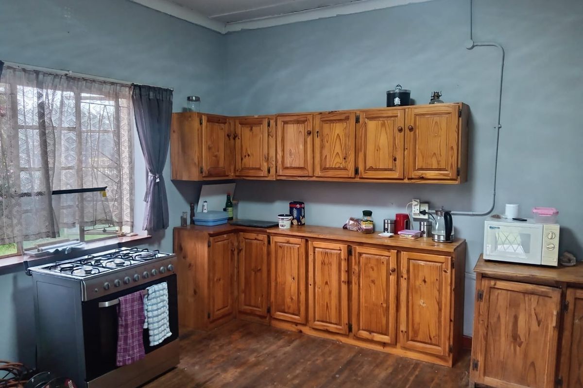 A functional kitchen featuring wooden cabinetry, a gas stove, and timber flooring, offering potential for modernization and aesthetic improvement.