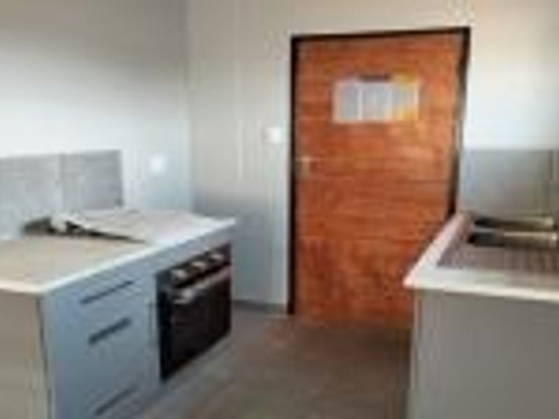 A functional kitchen area featuring built-in cabinetry, a hob, an oven, and a double sink with tiled splashbacks.
