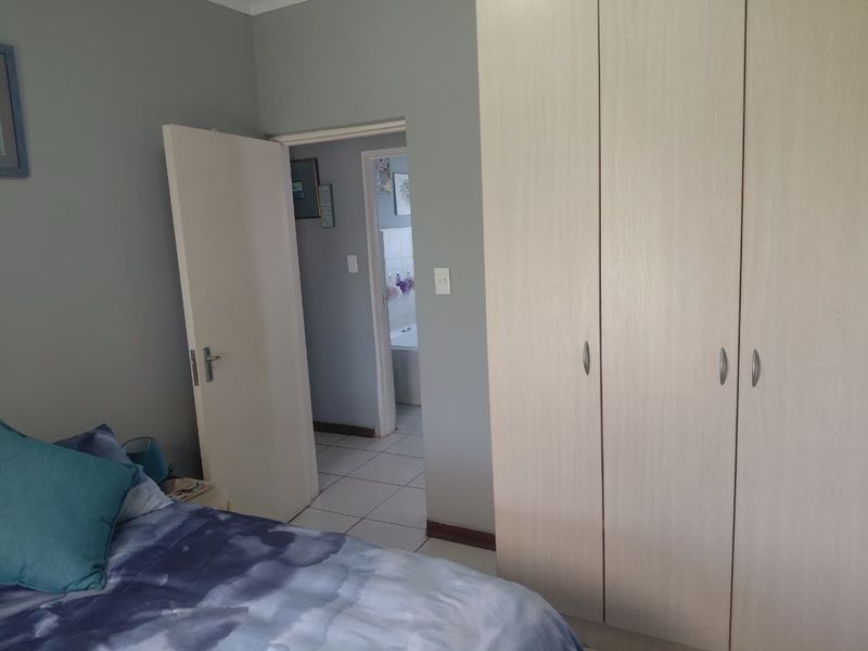 Bedroom featuring light-toned built-in cupboards and direct access to an adjoining bathroom.