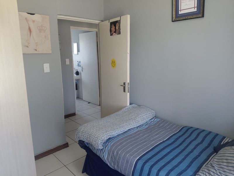 A bedroom featuring tiled flooring and access to an adjoining bathroom, providing a functional and neutral living space.