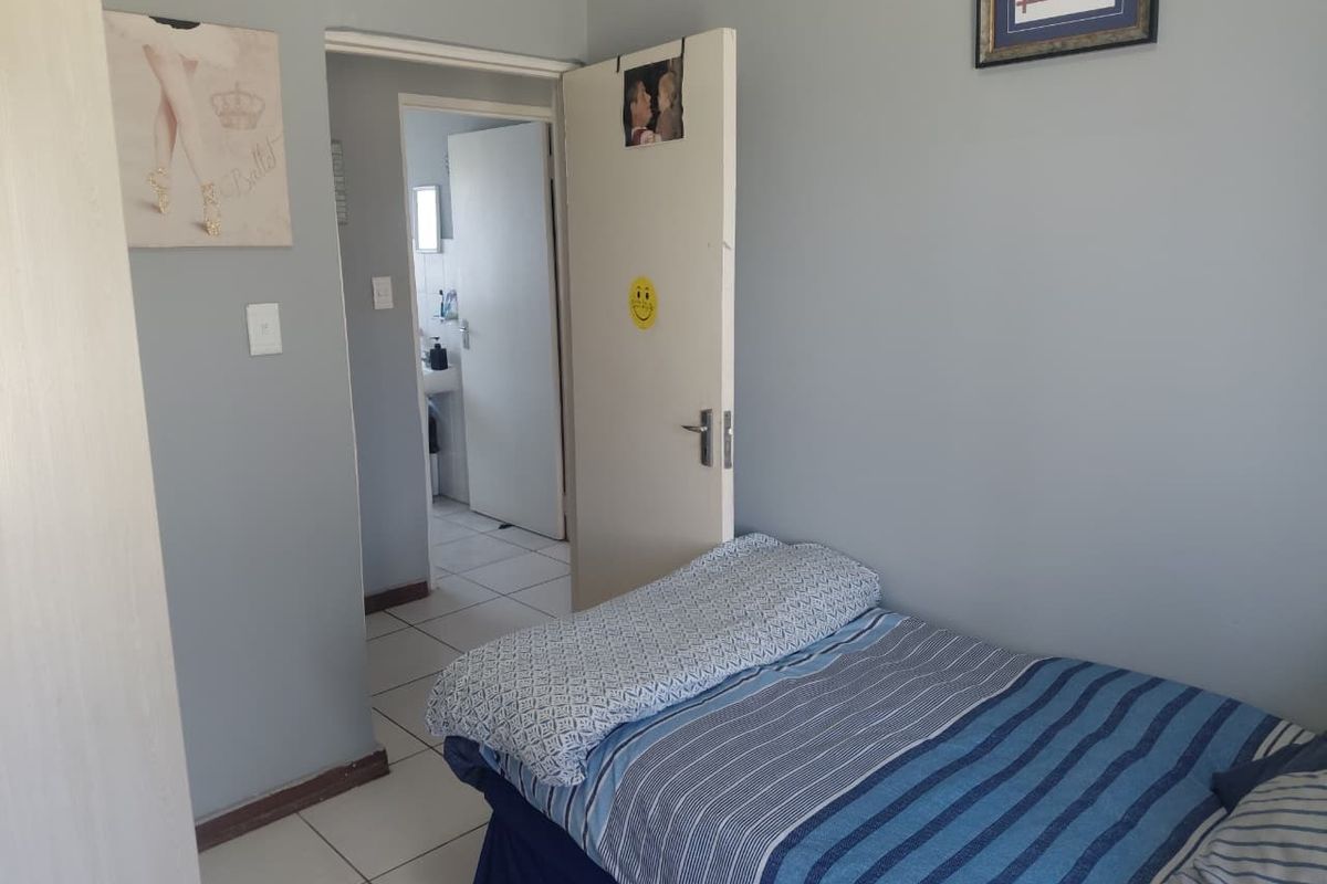 A bedroom featuring tiled flooring and access to an adjoining bathroom, providing a functional and neutral living space.