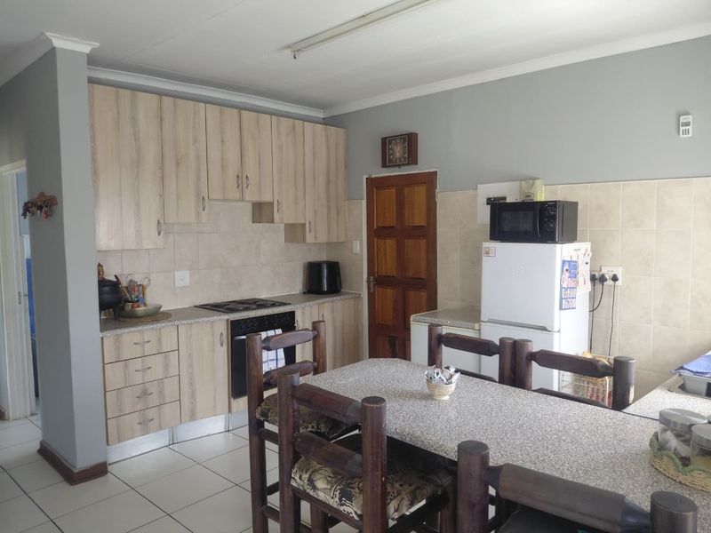 Functional kitchen featuring light wood-look cabinetry, tiled backsplash, built-in oven and hob, and tiled flooring, offering a practical layout for daily use.
