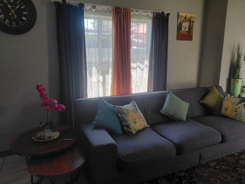 A living room area featuring a window with security bars and neutral wall finishes.