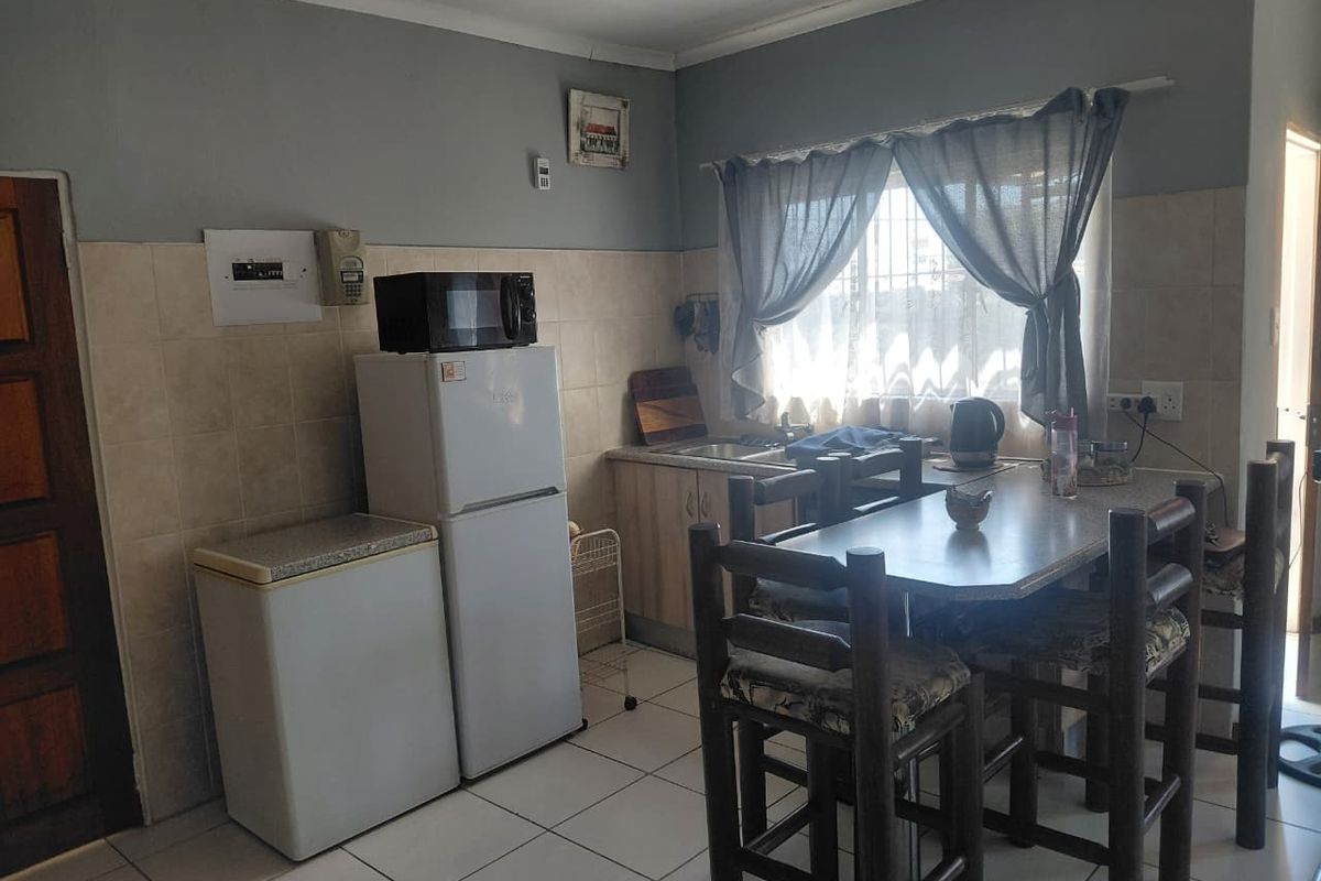 A functional kitchen featuring tiled flooring, tiled splashbacks, and built-in cabinetry with an integrated sink area.