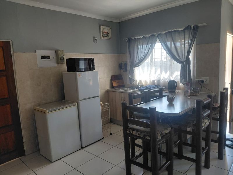 A functional kitchen featuring tiled flooring, tiled splashbacks, and built-in cabinetry with an integrated sink area.