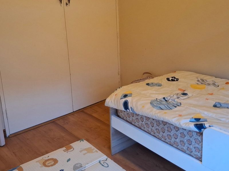 A functional bedroom featuring laminate flooring and built-in cupboards, providing essential storage space.