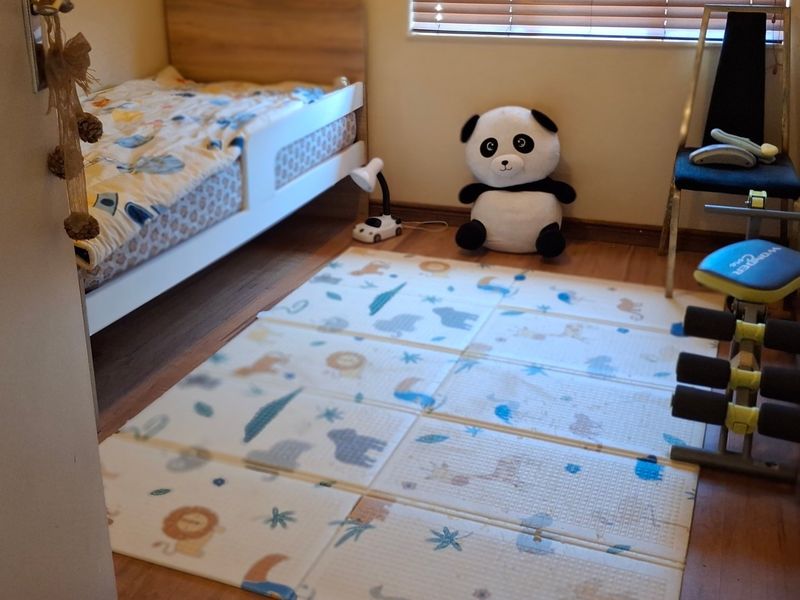 A bedroom featuring laminate flooring and venetian blinds, currently utilized as a child's room.