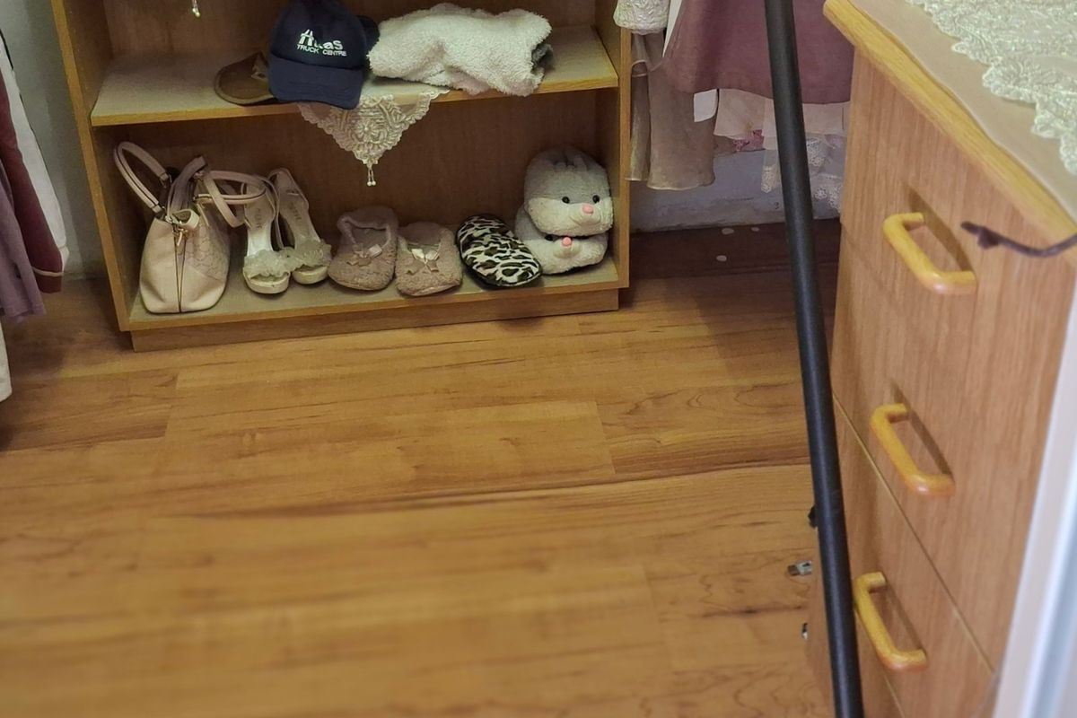 A view of a bedroom closet area featuring built-in wooden cabinetry and laminate flooring.