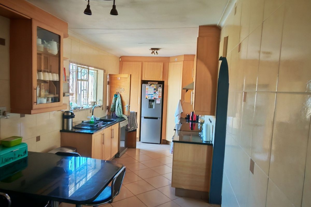 A functional kitchen featuring wooden cabinetry, tiled flooring, and wall splashbacks, offering a practical layout with ample storage and workspace.