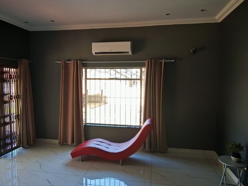 A living room featuring dark painted walls, large format tiled flooring, recessed lighting, and a sliding glass door providing access to the patio.