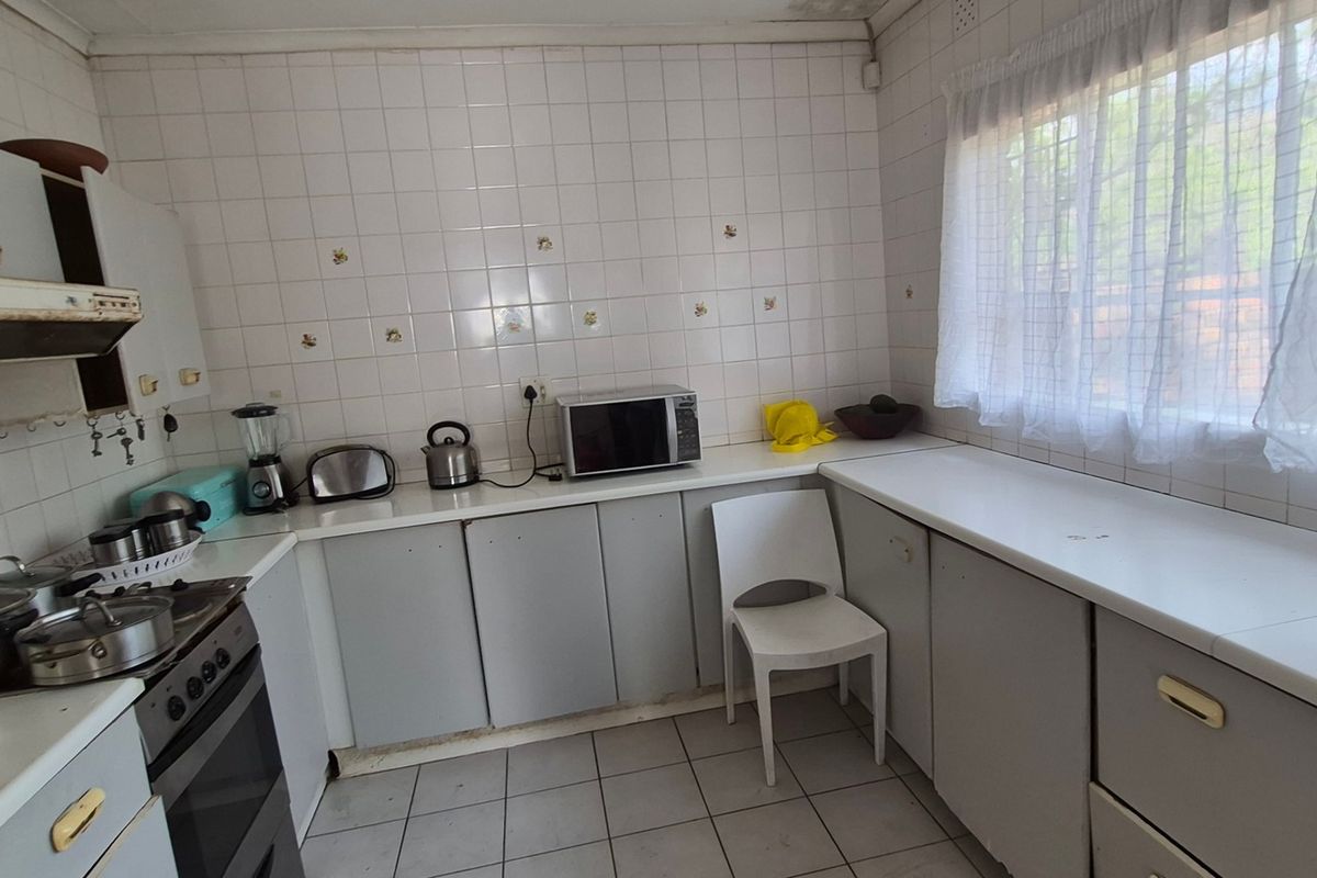A dated kitchen featuring tiled walls, built-in cabinetry, and a built-in oven with hob, offering potential for modernization and renovation.
