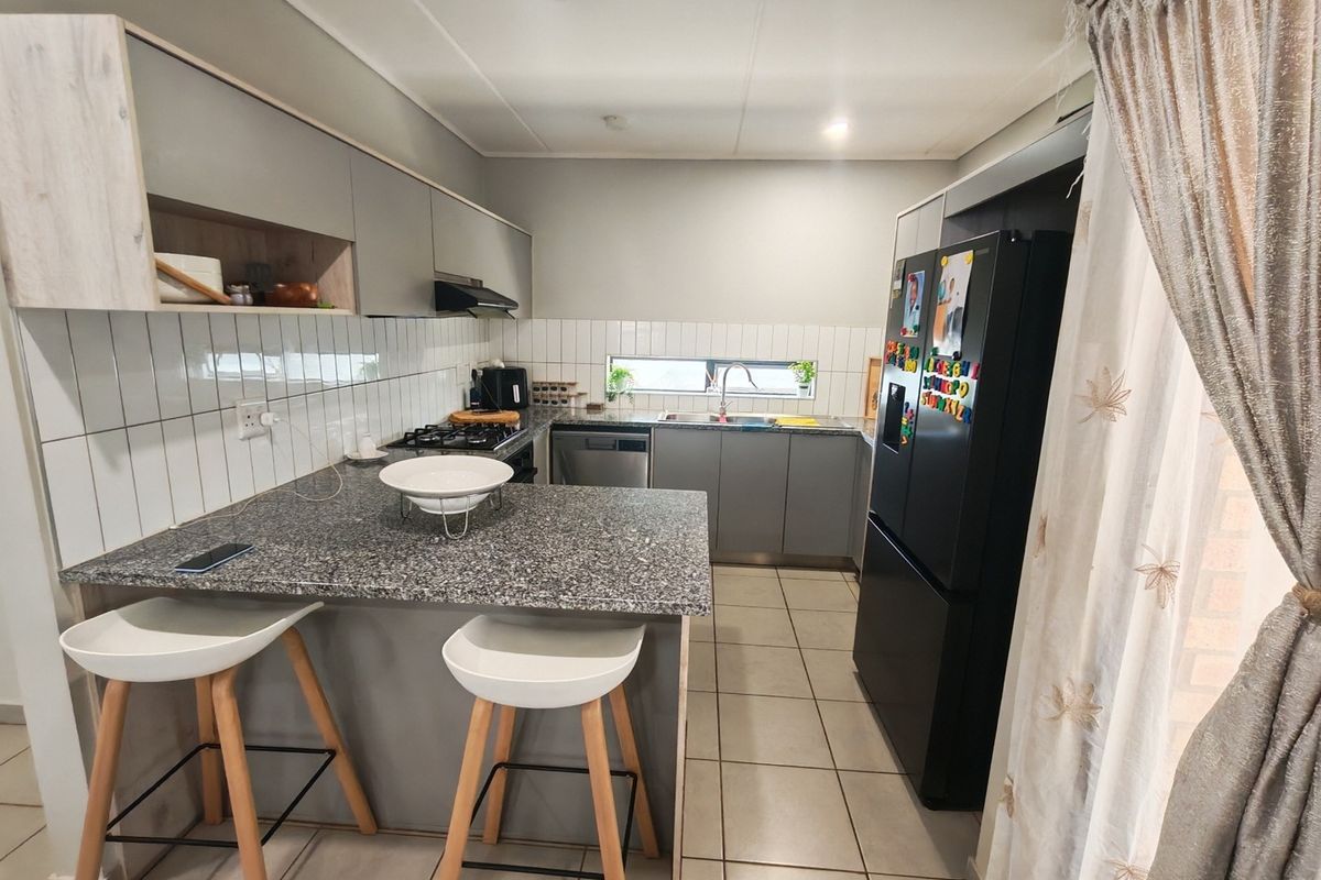 Modern kitchen featuring granite countertops, built-in cabinetry, gas hob, extractor fan, and tiled finishes, offering a functional and well-maintained cooking space.