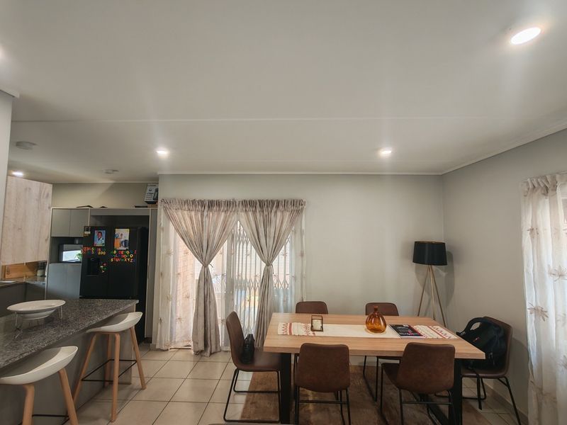 Open plan living and dining area featuring tiled floors, recessed lighting, and a kitchen breakfast bar with granite countertops and direct patio access.