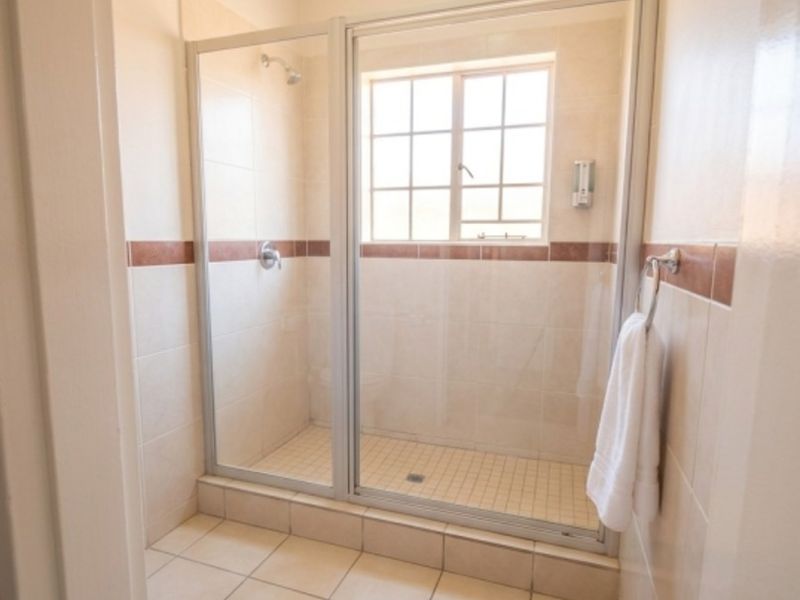 A clean, functional bathroom featuring a walk-in shower enclosure with tiled walls and flooring, providing a neutral and well-maintained space.