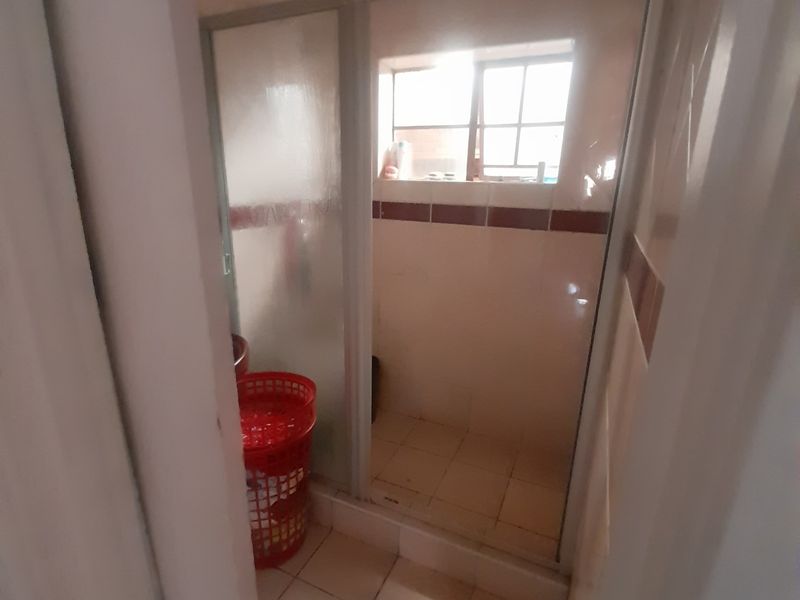A compact bathroom featuring a shower enclosure with tiled walls and flooring, offering a functional space ready for modernization.