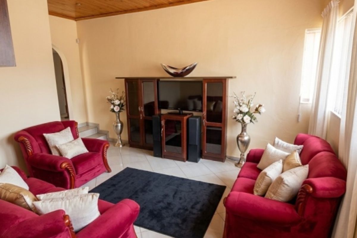 A living room featuring a warm timber tongue and groove ceiling, recessed lighting, and tiled flooring, creating a cozy and traditional atmosphere.