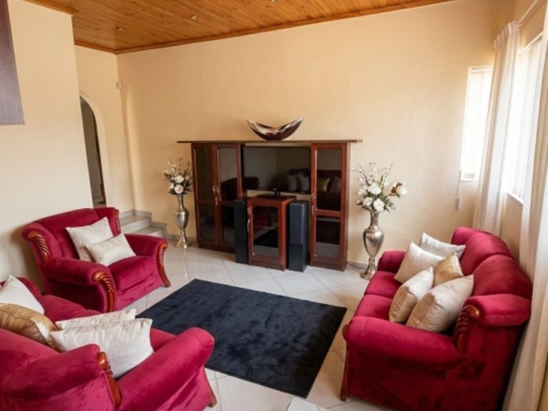 A living room featuring a warm timber tongue and groove ceiling, recessed lighting, and tiled flooring, creating a cozy and traditional atmosphere.