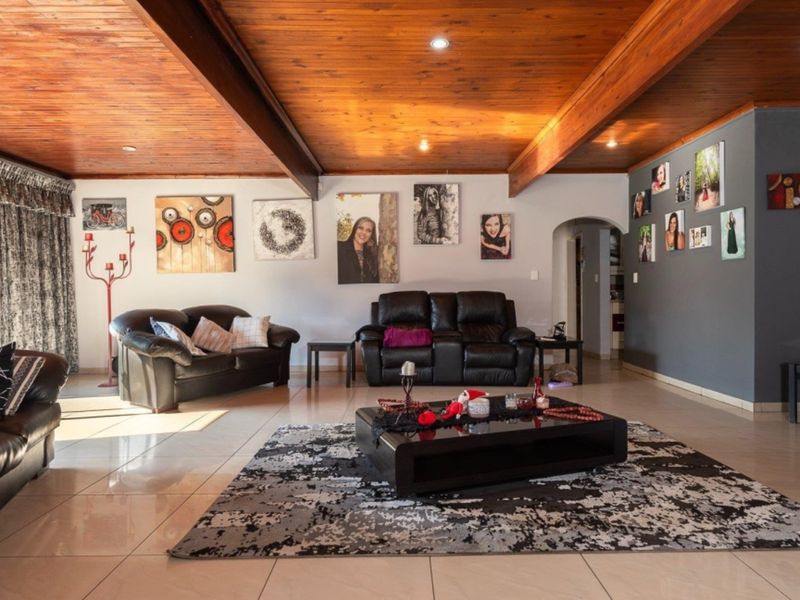 Spacious living room featuring a warm timber-clad ceiling with exposed beams, recessed lighting, and neutral tiled flooring, creating a comfortable and inviting atmosphere.