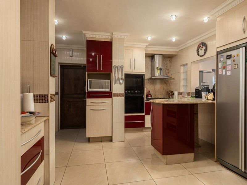 A well-maintained kitchen featuring two-tone cabinetry, integrated appliances, stone countertops, and tiled flooring with recessed lighting.