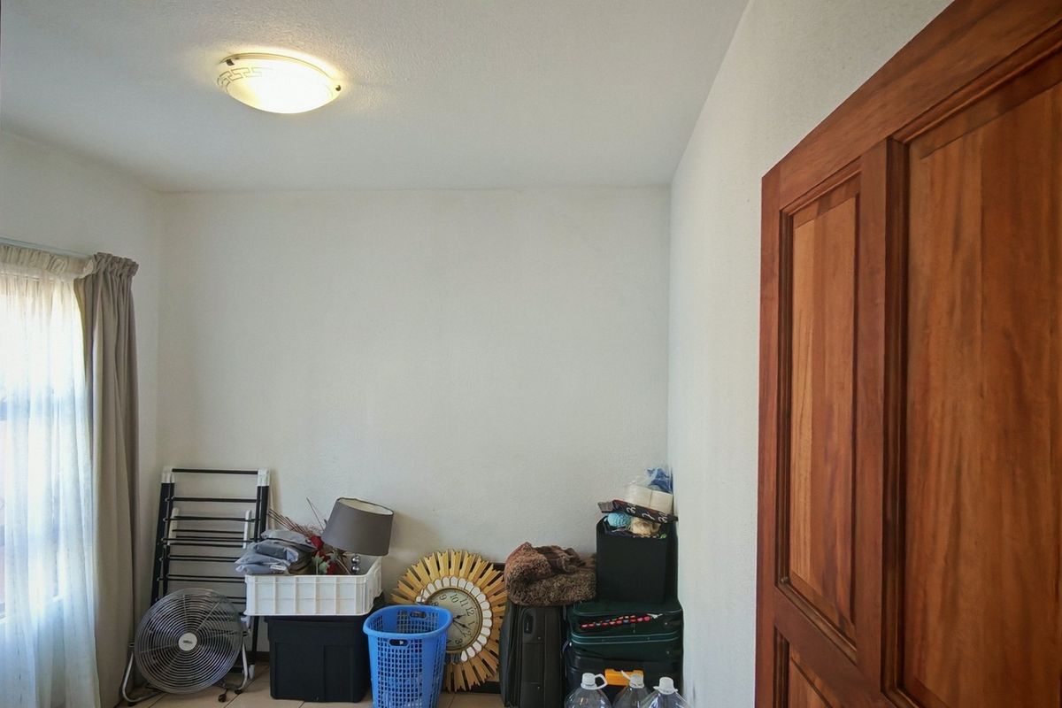 A simple bedroom space featuring a wooden door and a ceiling light fixture, offering a blank canvas for potential interior design updates.