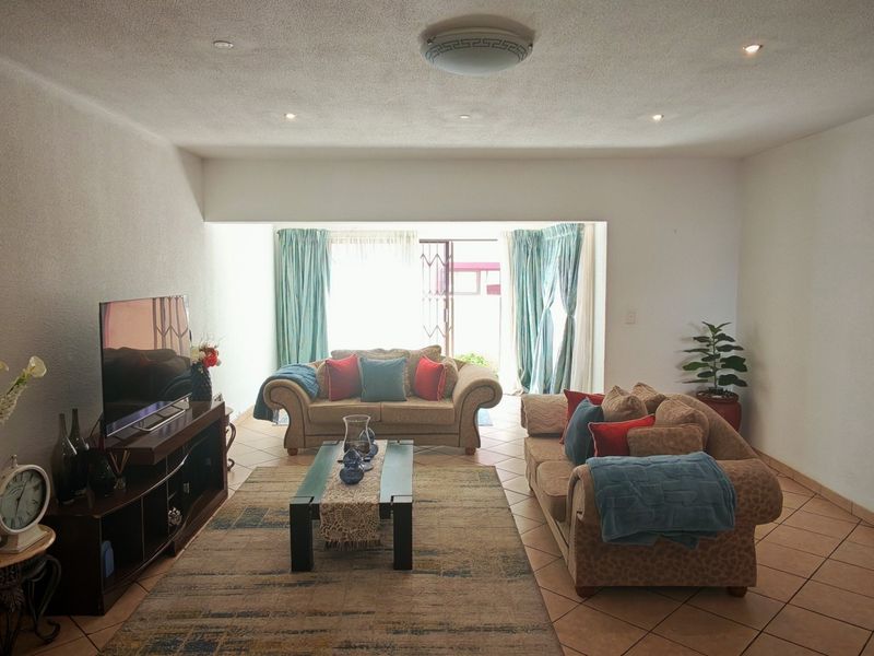 Spacious living room featuring tiled flooring, recessed lighting, and a sliding glass door providing access to the exterior.
