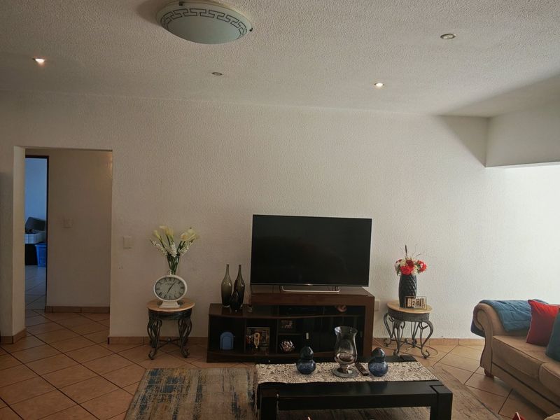 A living room featuring ceramic floor tiles, recessed downlights, and a textured ceiling, providing a functional and neutral space for relaxation.