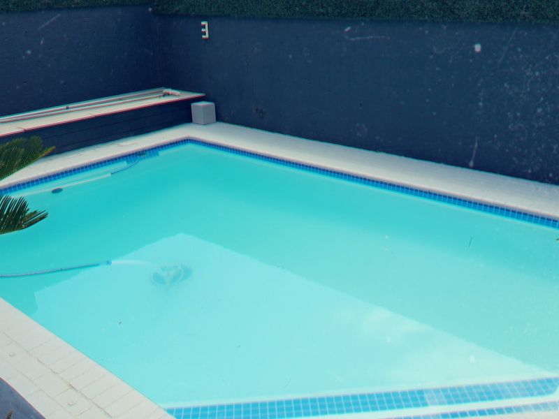 A private swimming pool area featuring tiled coping and a dark-painted retaining wall boundary.
