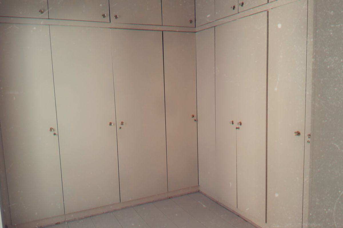 A bedroom featuring extensive built-in floor-to-ceiling cupboards with overhead storage, providing ample storage space.
