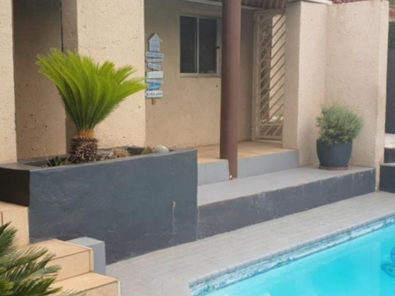 Outdoor pool area featuring a tiled patio, built-in planter box, and direct access to the home via a security gate.