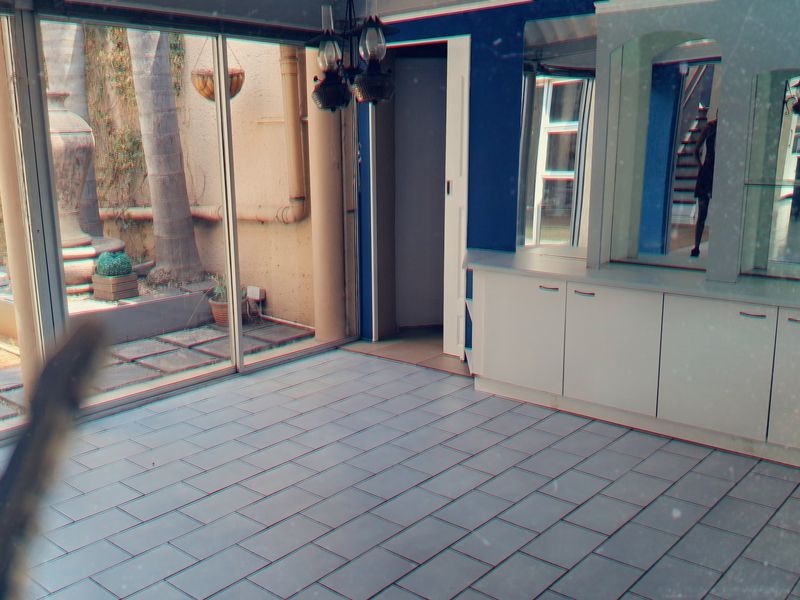An empty living area featuring tiled flooring, built-in cabinetry with mirrored accents, and large sliding glass doors providing access to the rear garden.