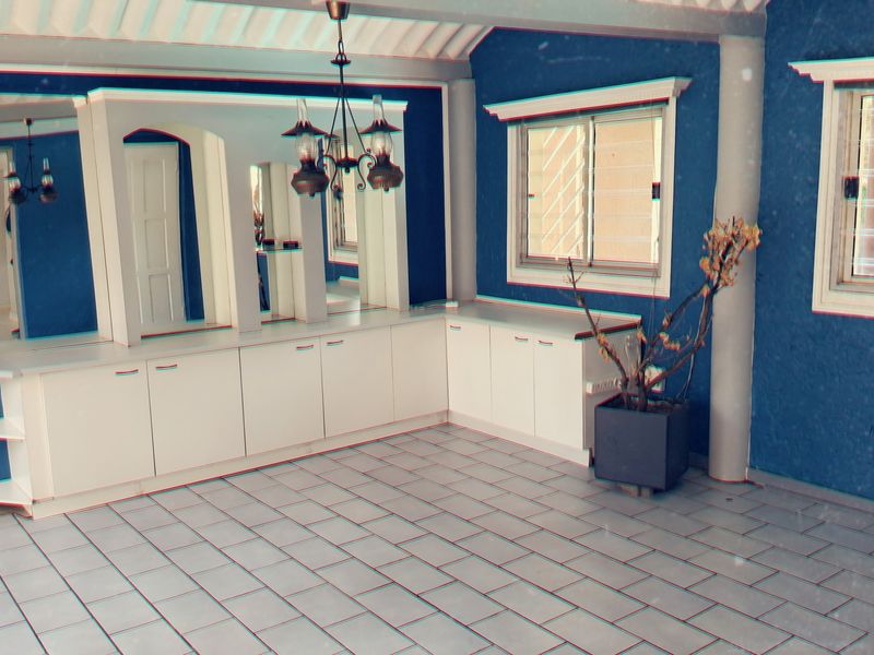 An empty living area featuring tiled flooring, built-in white cabinetry, and a large mirrored wall panel, providing a versatile space for customization.