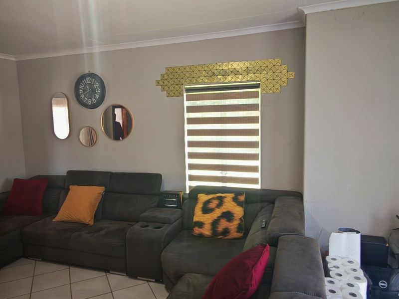 A living room featuring tiled flooring and window blinds, offering a functional space with neutral wall tones.