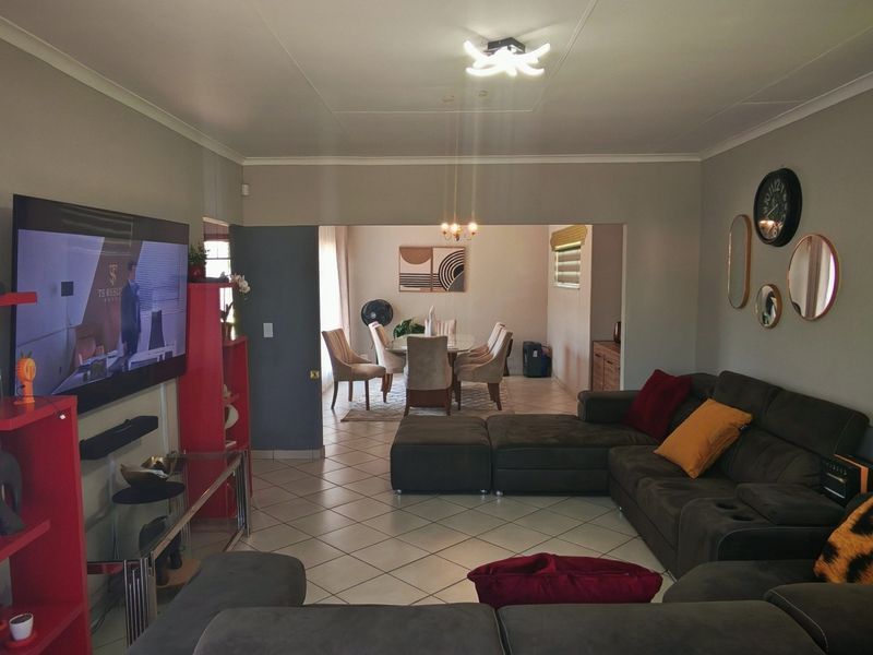 Spacious open-plan living and dining area featuring tiled flooring, neutral wall tones, and natural light through window blinds.