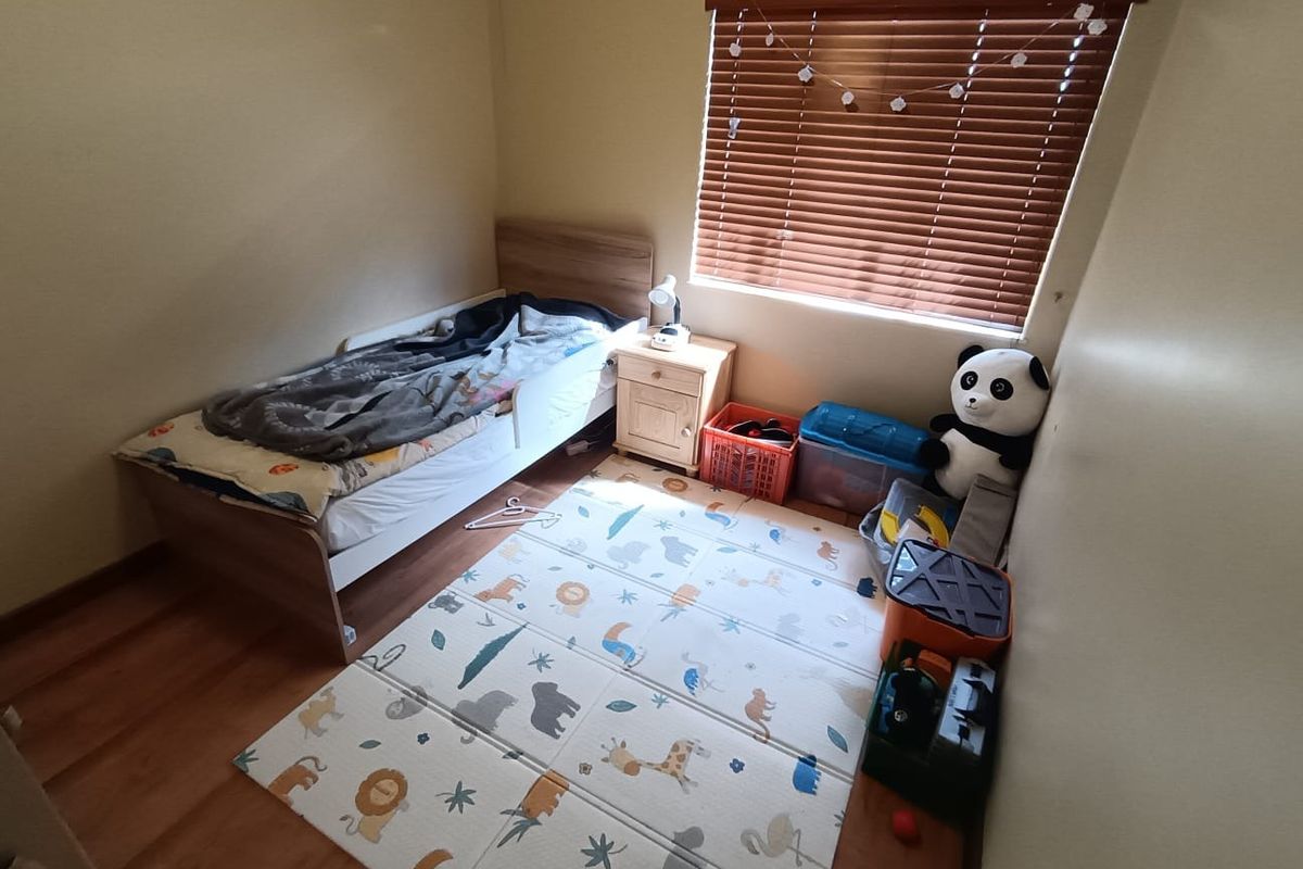 A compact bedroom featuring laminate flooring and fitted venetian blinds, providing a functional space suitable for a child's room or home office.