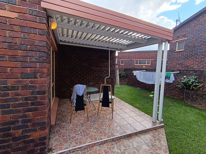 Covered patio area featuring a louvred roof and tiled flooring, providing a functional outdoor space adjacent to the garden.