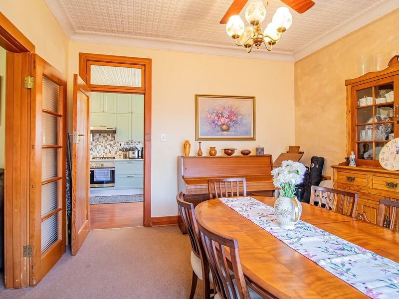 A traditional dining room featuring a pressed metal ceiling, timber door frames, and direct access to the adjacent kitchen area.