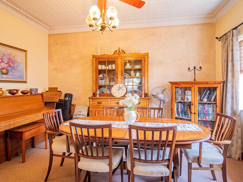 A traditional dining room featuring a decorative ceiling, ceiling fan, and large window, providing a warm and classic atmosphere for family meals.