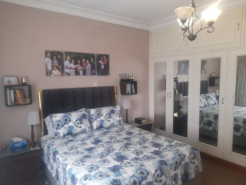 A bedroom featuring built-in wardrobes with mirrored doors, decorative ceiling coving, and a classic chandelier light fixture.