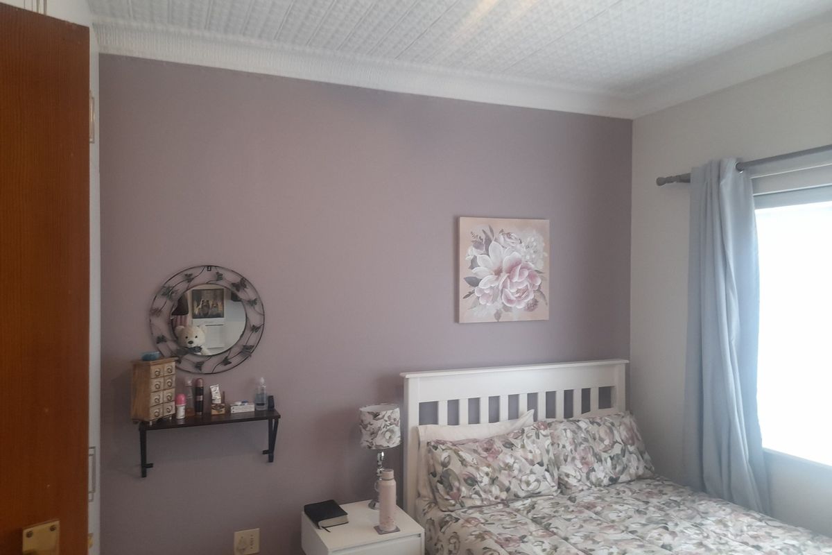A bedroom featuring a textured ceiling, coving, and a window with natural light.