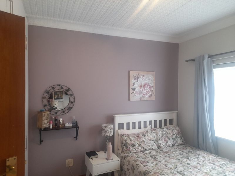 A bedroom featuring a textured ceiling, coving, and a window with natural light.