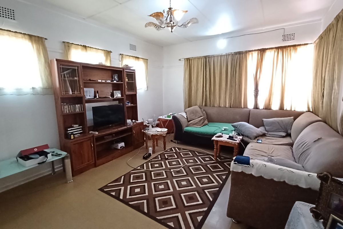 A spacious living room featuring classic ceiling cornices and ventilation grilles, offering a functional layout ready for modern updates and cosmetic improvements.