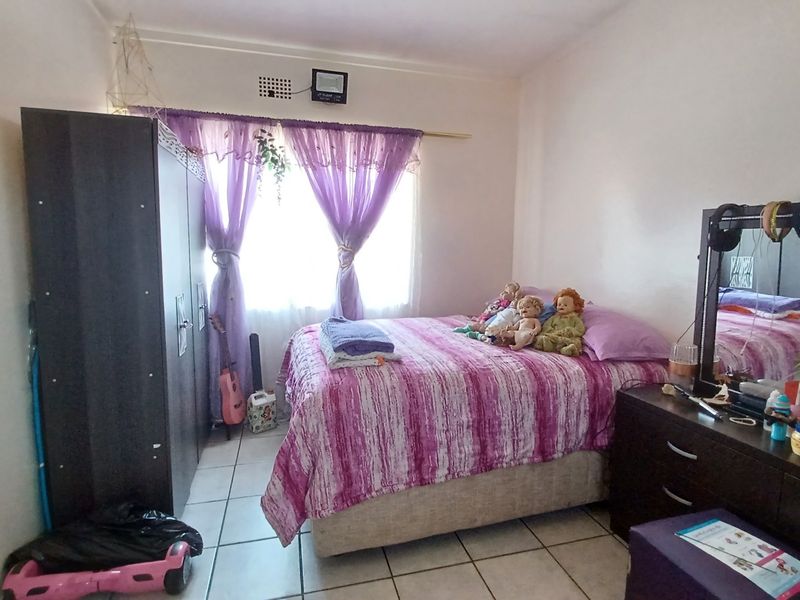 A bedroom featuring tiled flooring and a window with curtain rod, offering a functional space for rest.